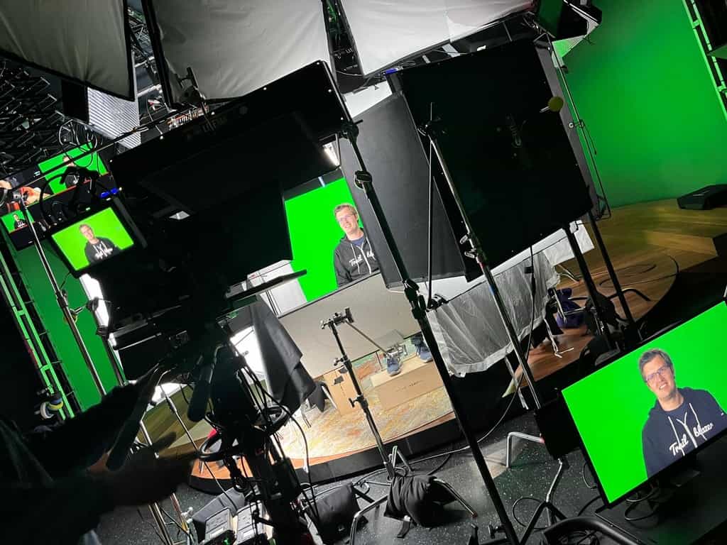 Chasing Clouds & Catching Up with the #CommerceCrew at Dreamforce 2023 4 Thomas Theunen sitting in between studio lights with a camera pointed at him. Multiple screens show his face.