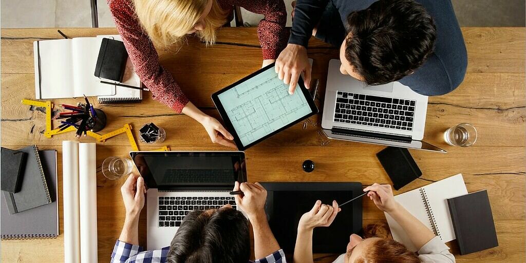 A group of people sitting at a table with laptops.